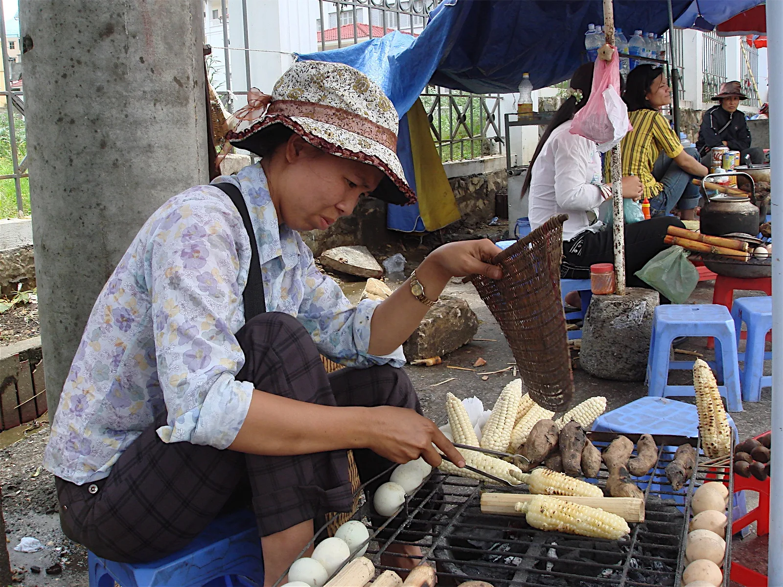 Vendeuse de street food proposant maïs grillé et patates douces à Sapa au Vietnam